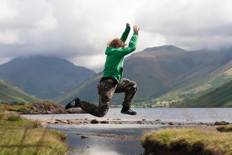 person jumping in front of mountains having used hypnosis for pain relief
