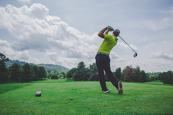 golfer driving off tee having undergone sports hypnotherapy to improve performance